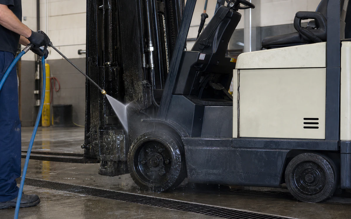 Wet greasy soil being rinsed from a protected electric forklift in a recovery wash bay